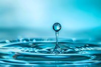 Single water drop splash creating crown ripple effect on turquoise blue surface with floating sphere droplet captured in high-speed macro photography.