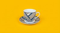 Porcelain teacup with saucer featuring blue diagonal stripe pattern, isolated on bright yellow background for design, merchandise, and hospitality projects.