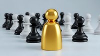 Golden leader figure standing out among black and white chess pawns representing leadership, strategy, and business success concepts.