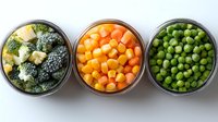 Frozen vegetables in glass bowls - broccoli florets, diced carrots and green peas arranged in row on white background, top view of healthy food ingredients.