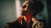 African American woman with closed eyes basking in warm sunlight, face illuminated with golden hour glow, expressing peaceful moment of mindfulness and serenity.