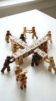 Wooden figurines arranged in circle around blocks spelling teamwork and collaboration, representing corporate unity and cooperative business strategy.