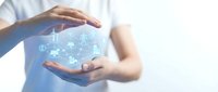 Hands protecting holographic renewable energy icons with wind turbines, solar panels and green technology symbols for sustainable development concepts.