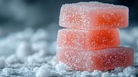 Stack of pink sugar-coated jelly candies on crystalline sugar surface with soft focus background, perfect for confectionery marketing.