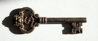 Antique bronze skeleton key with ornate floral head design, isolated on white background, suitable for vintage decor, steampunk projects, and historical themed designs.