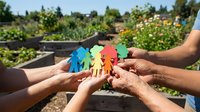 Multiple diverse hands holding colorful paper cutout figures together in community garden setting, representing teamwork, unity, cooperation, and social connection for nonprofit campaigns.