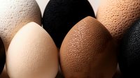 Fresh eggs in different natural colors from light cream to dark brown and black arranged in minimalist composition on neutral background for food design.