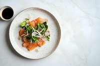 Fresh salmon sashimi served on ceramic plate with green salad, daikon radish sprouts and soy sauce on marble background. Food photography.