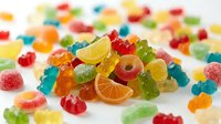 Colorful assorted gummy candies and jelly sweets scattered on white background. Variety of fruity gummi bears, rings and shapes for confectionery concepts.