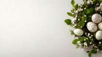 Speckled Easter eggs nestled in fresh green foliage with delicate white spring blossoms against clean white background. Perfect for seasonal holiday designs.