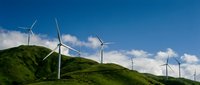 Wind turbines on green rolling hills under blue sky with white clouds, representing renewable energy and sustainable power generation for environmental and industrial projects.