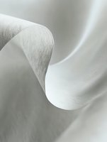 Elegant white paper curve creating gentle flowing lines and soft shadows against light background, abstract minimalist composition for modern design projects.