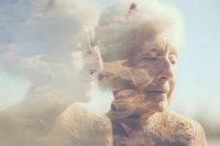 Ethereal double exposure portrait of elderly Asian woman with peaceful expression merged with cloudy sky, representing memory, aging, and spiritual journey.