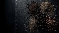 Assorted legumes and grains scattered on dark slate surface creating rustic culinary composition for healthy cooking and nutrition concepts.
