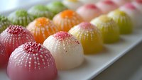 Colorful assorted mochi ice cream balls with coconut flakes arranged on white plate. Japanese dessert sweets in rainbow colors for cafe menu and food photography.