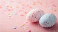 Pastel colored Easter eggs decorated with red speckles on pink background with scattered confetti dots, creating festive spring holiday atmosphere.
