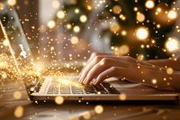 Female hands typing on laptop keyboard with magical golden bokeh lights and sparkles creating dreamy atmosphere for business or holiday season concept.