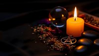 Mystical altar setup with burning candle, crystal ball, pentagram symbol and dried herbs for spiritual rituals, fortune telling and esoteric practices.