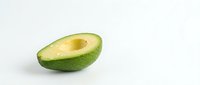 Fresh avocado half with pit removed on white background, healthy organic fruit for cooking and nutrition concepts.