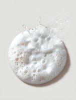 White soap foam with bubbles and splash on beige background, circular shape with dynamic water motion and delicate texture for cosmetic and hygiene concepts.