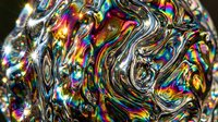Liquid metal surface with vibrant rainbow iridescent swirls and flowing patterns, creating an abstract holographic effect suitable for backgrounds and digital design projects.