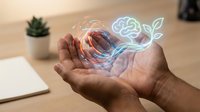 Hands holding holographic brain and plant icons representing artificial intelligence, growth, and innovation in modern technology workspace.