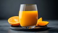 Fresh orange juice in glass with sliced citrus fruit on dark background, healthy vitamin drink for breakfast, natural refreshment.