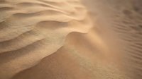 Close-up of rippled sand texture with warm golden light creating shadows across undulating surface, suitable for backgrounds and nature designs.
