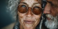 Elderly couple with freckled skin and vintage glasses sharing intimate moment, showcasing aging beauty and lifelong companionship in warm portrait.