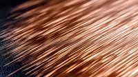 Macro shot of copper wire strands creating diagonal lines and patterns against dark background. Metallic texture with warm tones and selective focus.