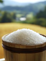 Raw white rice grains in traditional wooden measuring cup against blurred rural landscape background, showcasing natural farm-to-table concept and Asian culinary ingredients.