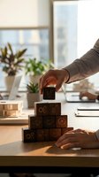 Male professional with medium skin tone placing wooden block with gear icon on stacked blocks featuring business symbols, representing strategy and growth in modern office setting.