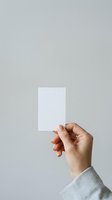 Hand holding blank white card isolated on neutral background, ready for custom branding, business messaging, or promotional design applications.