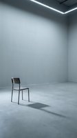 Minimalist interior with single modern chair in empty concrete room with linear ceiling lights, suitable for contemporary design and architectural concepts.