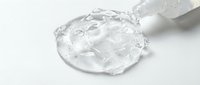 Clear gel or liquid serum pouring from bottle onto white surface, isolated cosmetic product for skincare, beauty, and wellness design applications.