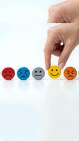 Hand selecting yellow smiley face among emotion spheres representing satisfaction, feedback, and customer service rating on white background.