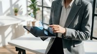 Professional businesswoman using digital tablet with holographic interface in modern office workspace for technology and innovation concepts.