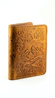 Handcrafted tan leather bifold wallet with embossed mountain landscape and oak leaves, isolated on white background, ready for design use.