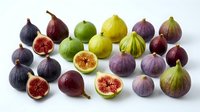 Fresh figs in various stages of ripeness arranged on white background, whole and halved fruits showing red flesh, suitable for food photography, culinary content, healthy eating and nutrition design projects.