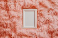 White rectangular frame on coral pink faux fur background creating soft luxurious texture and minimalist composition for modern interior design and social media content.