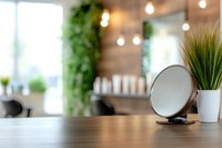 Modern beauty salon interior with round mirror and decorative plant on wooden counter, featuring soft lighting and green wall elements in background.