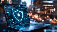 Glowing cybersecurity shield icon on laptop screen with digital interface elements against blurred city lights background, representing data protection technology.