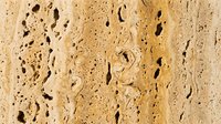 Porous travertine stone texture with natural holes and cavities in warm beige tones for architectural and interior design projects.