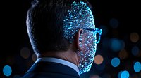 Businessman with glowing blue digital particles overlaying half face, representing artificial intelligence and digital transformation in dark background.