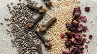 Assorted spices and seeds arranged on burlap including coriander, cloves, white peppercorns and dried chili peppers for culinary cooking and seasoning.