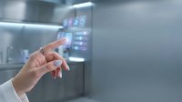 Hand touching digital interface on modern smart appliance with holographic display showing control options for kitchen automation and IoT connectivity.