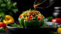 Colorful quinoa salad served in halved green bell peppers with fresh vegetables and herbs, drizzled with dressing on dark background. Food styling.