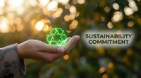 Caucasian hand holding glowing green recycling symbol against blurred natural background with warm bokeh lights, representing environmental responsibility and sustainable business practices.
