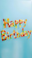 Happy Birthday text made from colorful gummy bears and candy on soft blue background. Festive greeting card design for celebrations and party invitations.