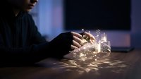 Young male professional holding glowing digital cube with illuminated network connections and data streams, representing technology innovation, artificial intelligence, and business solutions.